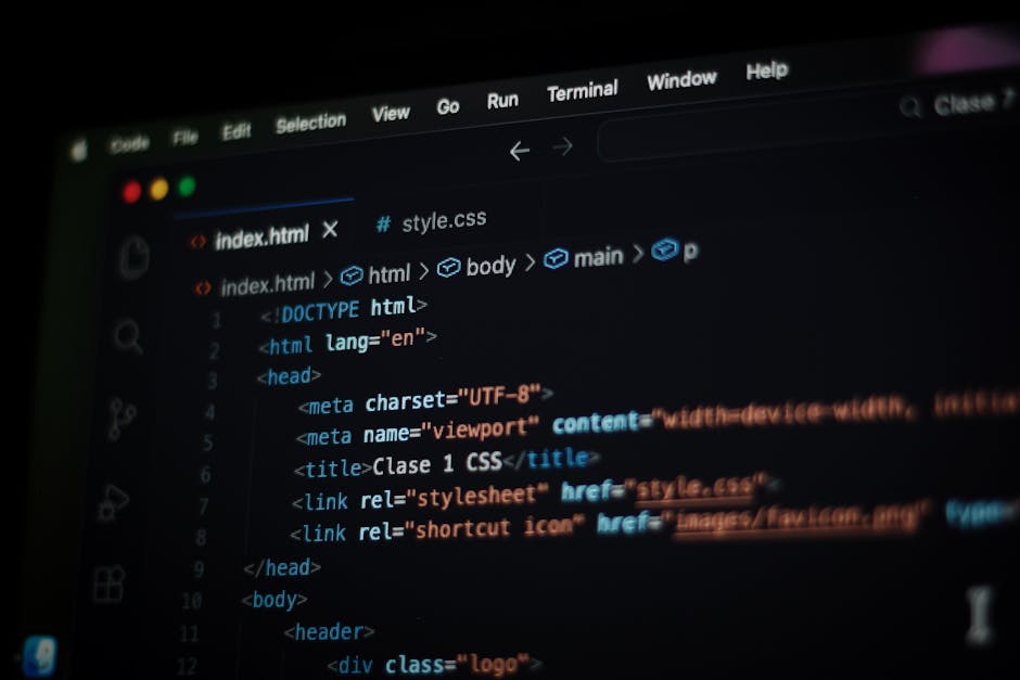 Close-up photograph of a computer screen displaying lines of HTML code with various tags and attributes highlighted in different colours, including red, green, blue, and yellow. The code references a