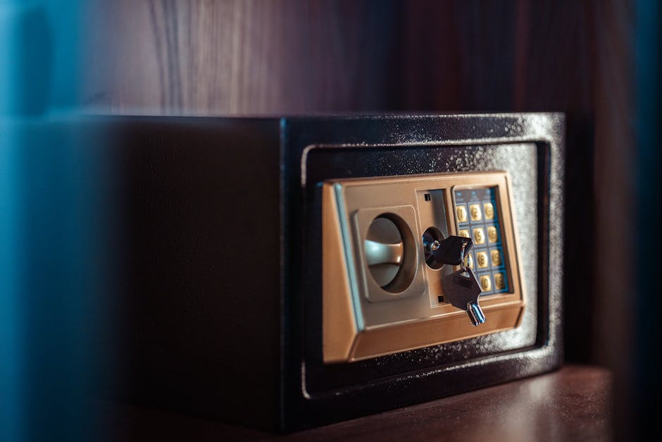 A man with a blurred face and wearing gloves is holding a smartphone in his hands, positioned in front of an open jewelry box that is lined with red fabric. Inside the box, various pieces of jewelry i